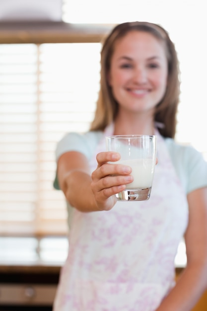 Portrait einer Frau, die ein Glas Milch gibt