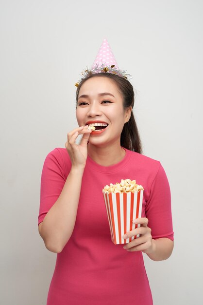 Portrait einer lachenden Frau, die Popcorn lokalisiert über weißem Hintergrund hält