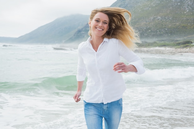 Portrait einer lächelnden Frau, die am Strand läuft