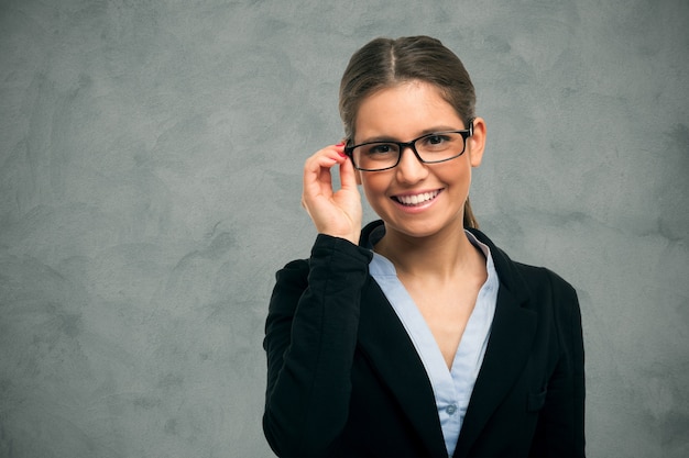 Portrait einer lächelnden schönen Frau, die ihre Brillen anhält