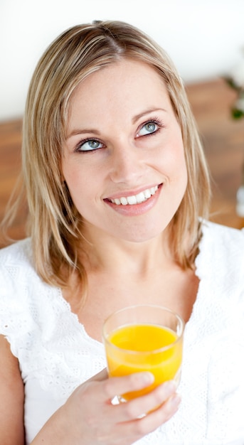 Portrait einer leuchtenden Frau, die einen Orangensaft anhält