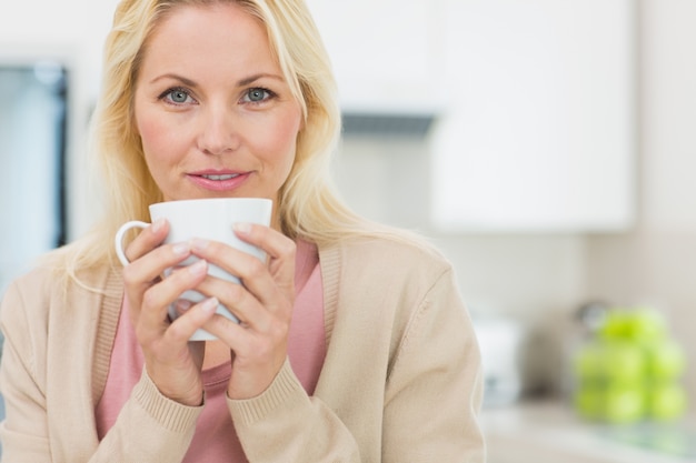 Portrait einer schönen Frau mit Kaffeetasse in der Küche