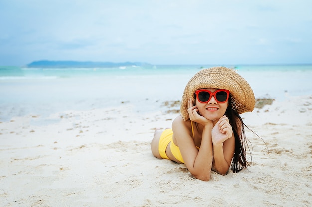 Portrait einer schönen Frau mit Sonnenbrille und Bikini am Strand.