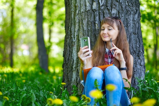 Portrait einer schönen jungen Frau selfie im Park mit einem Smartphone
