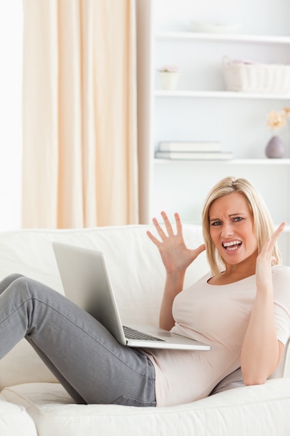 Portrait einer unglücklichen blonden Frau mit einem Laptop