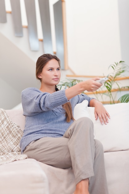 Portrait eines Frauenkanal mit einer Fernbedienung