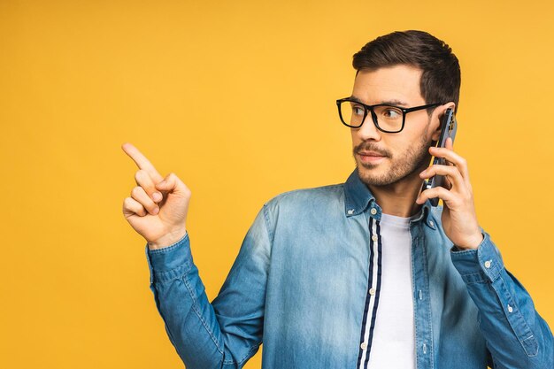 Portrait eines freudigen jungen Mannes, der einen Handy hält Glücklicher Sieger, der Finger zeigt