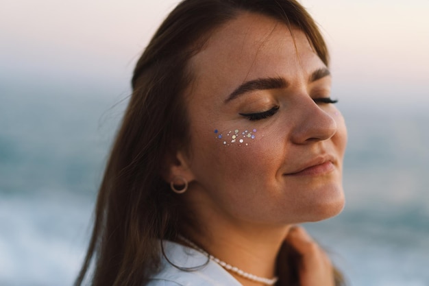 Portrait eines glücklichen jungen Mädchens mit geschlossenen Augen auf einem Hintergrund des schönen Meeres