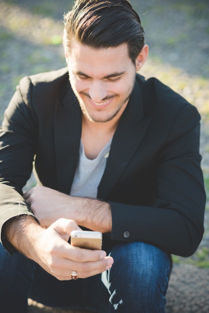 Portrait eines jungen italienischen Jungen, der einen Smartphone verwendet