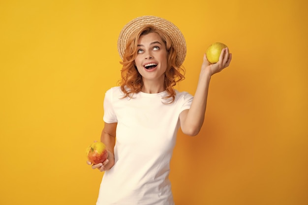 Portrait eines lächelnden glücklichen Mädchens mit dem Apfel lokalisiert über gelbem Hintergrund