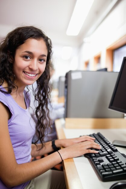Portrait eines netten lächelnden Studenten mit einem Computer