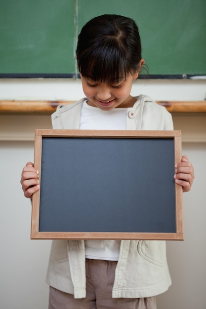 Portrait eines netten Mädchens, das einen Schule Schiefer anhält