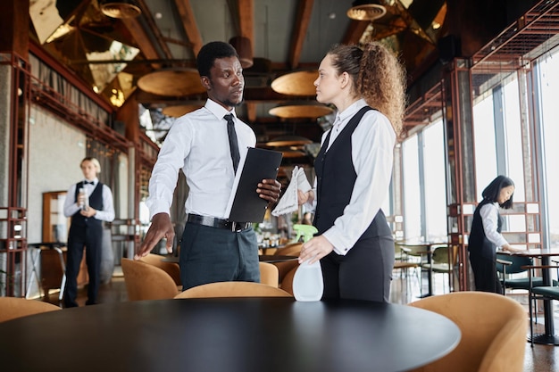 Portrait eines schwarzen Mannes als Manager, der Server ausbildet, den Speisesaal in einem Luxusrestaurant reinigt