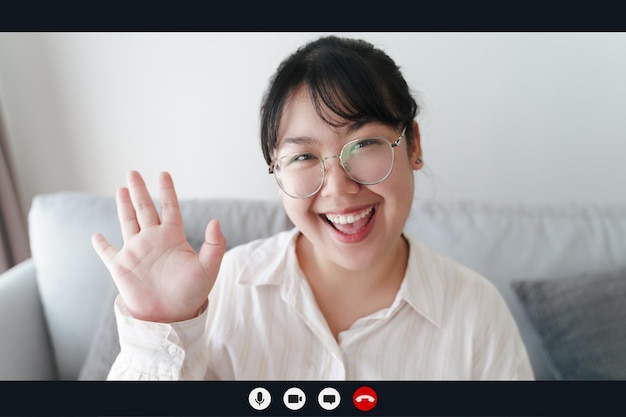 Portrait glückliche Frau, die zu Hause per Videokonferenz arbeitet und mit der Hand winkt