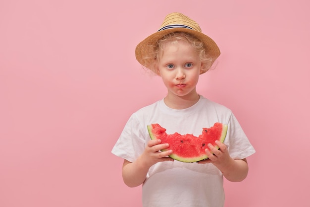 Portrait glückliches junges kleines Mädchen hält Scheibe Wassermelone über buntem rosa Hintergrund