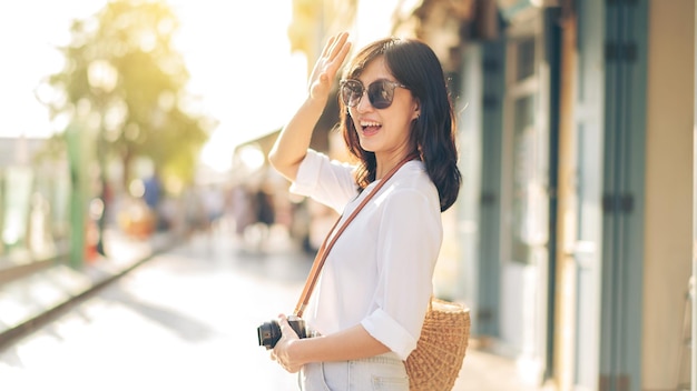 Foto portrait junge schöne asiatische frau mit kamera erkunden straße im sommerurlaub in bangkok thailand