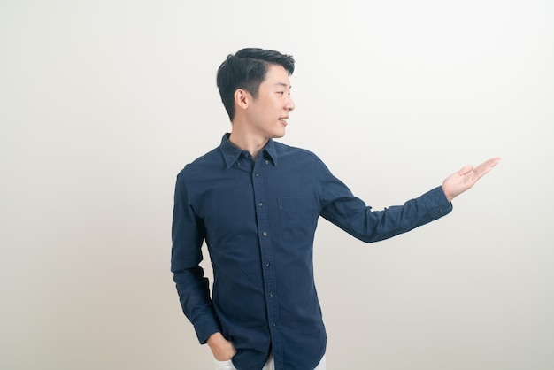 Portrait junger asiatischer Mann mit der Hand, die auf weißem Hintergrund zeigt oder präsentiert