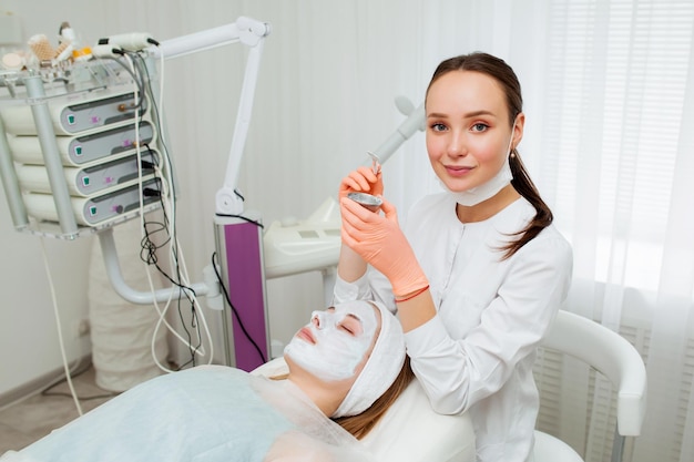 Portrait Kosmetikerin, die im Spa-Salon eine Maske auf das Gesicht des Kunden aufträgt. Wellness-Center Beruf im Gesundheitswesen