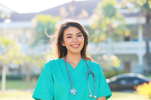 Portrait lächelnde Krankenschwester in Schrubbuniform, die im Park des Krankenhauses steht