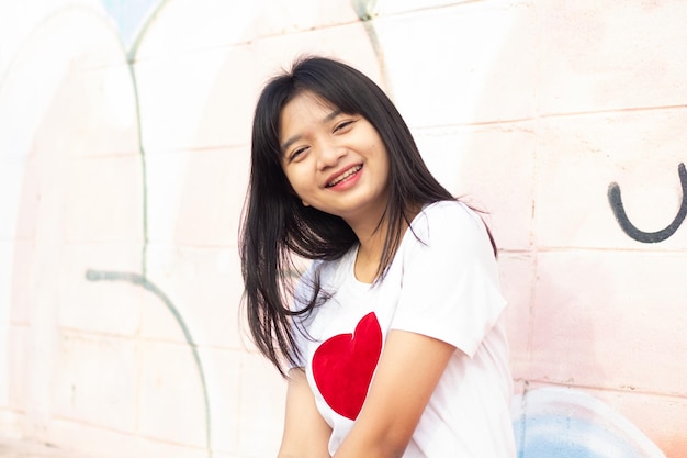 Portrait Nahaufnahme Gesicht Asiatisches junges Mädchen mit T-Shirt mit Herz auf buntem Hintergrund