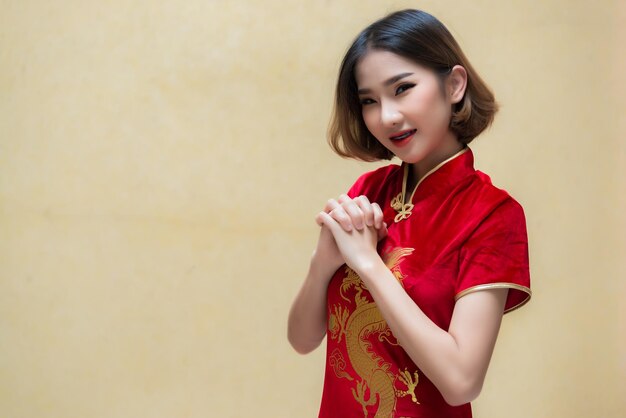 Portrait schöne asiatische Frau in Cheongsam-KleidThailänderFröhliches chinesisches NeujahrskonzeptFröhliche asiatische Dame in traditioneller chinesischer Kleidung mit einem roten Umschlag