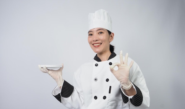 Portrait schöne asiatische Köchin mit Kochuniform, die Geste macht