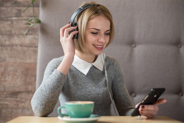 Portrait schöne Frau mit Kopfhörer genießen Sie Musik, während sie im Café sitzt und Kaffee trinkt