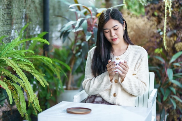 Portrait schöne junge asiatische Frau Mädchen in warmer Kleidung trinkt gerne positiv die Tasse Kaffeemilch oder Schokolade zu Hause im Wohnzimmer drinnen oder im Café