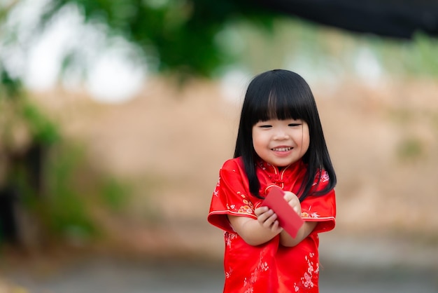 Portrait schönes asiatisches kleines Mädchen in Cheongsam-KleidThailand-MenschenFröhliches chinesisches NeujahrskonzeptGlückliches kleines asiatisches Mädchen in traditioneller chinesischer Kleidung