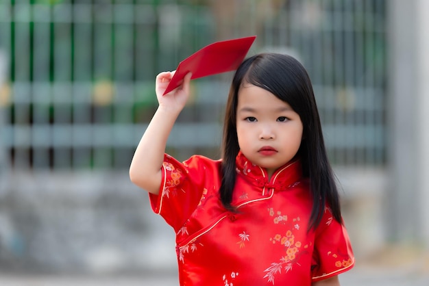 Portrait schönes asiatisches kleines Mädchen in Cheongsam-KleidThailand-MenschenFröhliches chinesisches NeujahrskonzeptGlückliches kleines asiatisches Mädchen in traditioneller chinesischer Kleidung