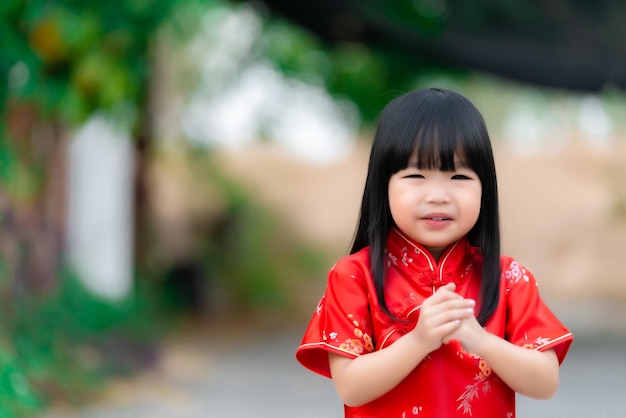 Portrait schönes asiatisches kleines Mädchen in Cheongsam-KleidThailand-MenschenFröhliches chinesisches NeujahrskonzeptGlückliches kleines asiatisches Mädchen in traditioneller chinesischer Kleidung