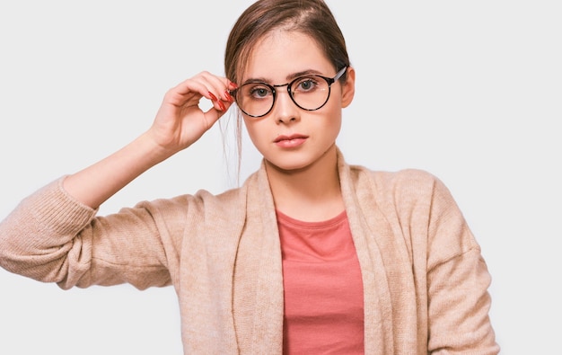 Portrait von ernsthaften jungen Brünette Frau hat müde Gesichtsausdruck trägt eine Brille und rosa Casual-Outfit isoliert über weißem Hintergrund Horizontale Schuss ziemlich traurige Frau