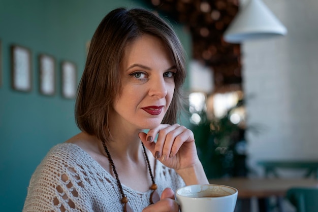 Portrait von Frau mittleren Alters trinkt Kaffee auf im Café Portrait von brunette Mädchen sitzt am Tisch im Café