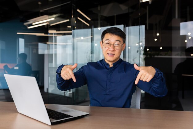 Portrait von Geschäftsmann mit Laptop im Büro Mann lächelnd und Blick in die Kamera zeigt mit