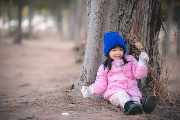 Portrait von süßen asiatischen kleinen Mädchen tragen Winterkleidung im Wald des ParksThailänder posieren für ein FotoGlückliche Zeit