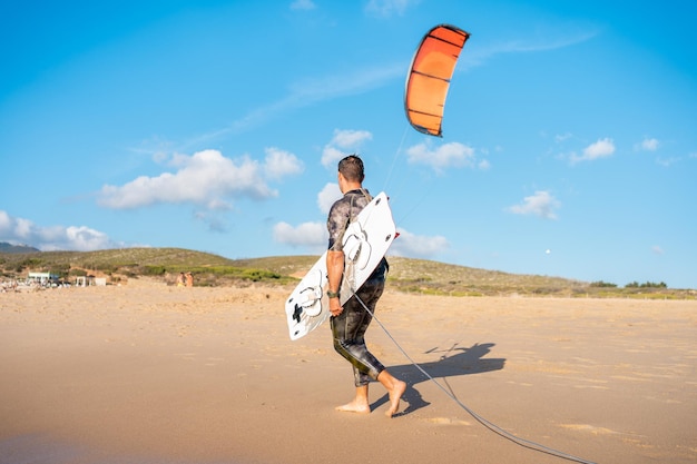 Portrait Wave Kitesurfer Walking Beach mit seinem Board und Kite