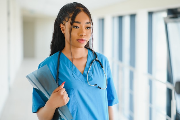 Foto portrait zuversichtlich afroamerikanische ärztin arzt schreiben patientennotizen isoliert auf krankenhaus klinik flur fenster hintergrund. positiver gesichtsausdruck