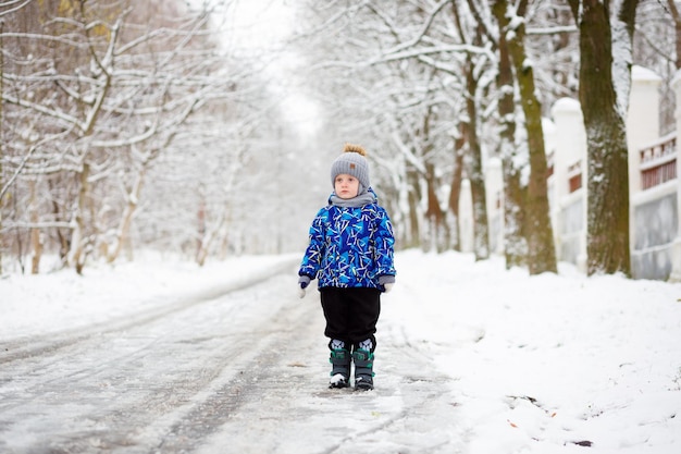Un portret de niño hermoso en sus brazos en invierno cerca de la casa con un árbol de navidad cubierto de nieve en un fondo