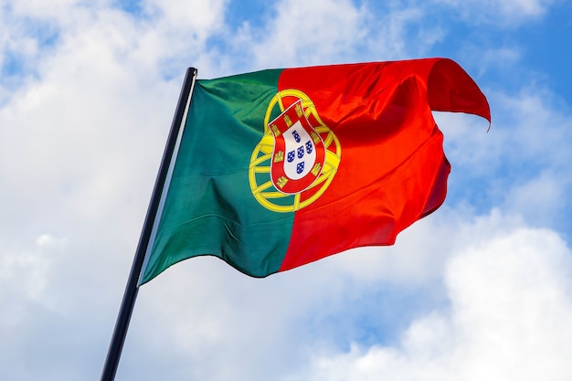 Portugiesische Flagge, die vor einem blauen Himmel weht.