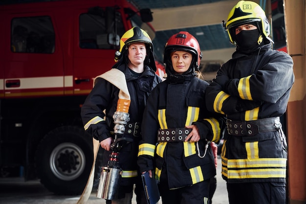 Posando para una cámara Grupo de bomberos con uniforme protector que está en la estación