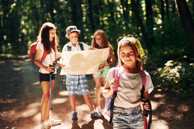 Posando para la cámara Niños paseando por el bosque con equipo de viaje