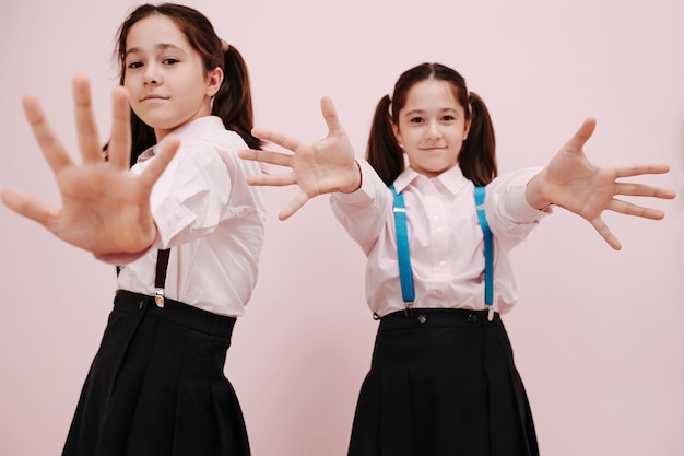 Posando colegialas gemelas con colas gemelas con las manos en la cámara