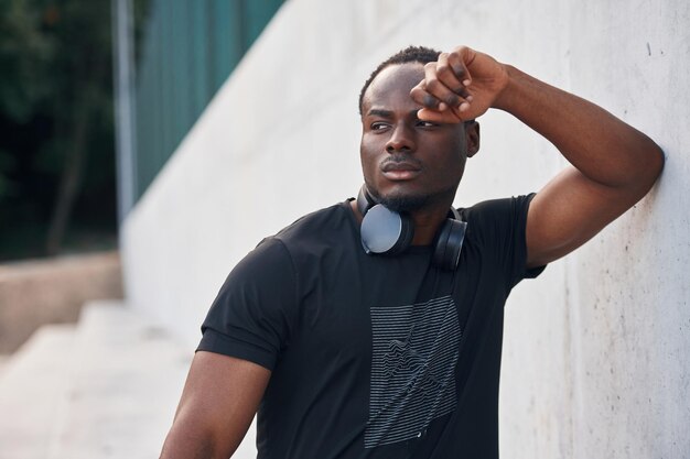 Posando e de pé Um belo homem preto está ao ar livre durante o dia