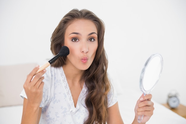 Foto posando morena atractiva sosteniendo un cepillo y un espejo