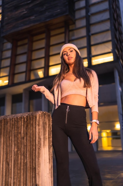 Posando na cidade em uma noite de inverno usando um suéter de malha rosa e chapéu