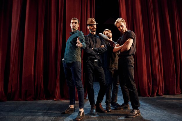 Posando para uma câmera Grupo de atores em roupas de cor escura em ensaio no teatro