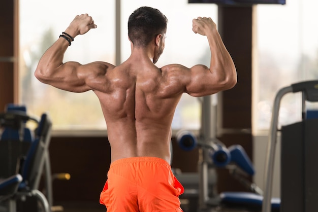 Pose de bíceps de un hombre joven en el gimnasio