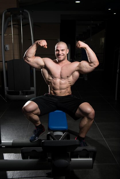 Pose de bíceps de un hombre joven en el gimnasio