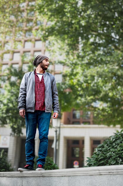 Foto pose contemplativa joven en ropa casual de pie en una pared perdido en la contemplación