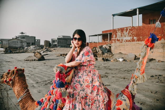 Pose frontal de chica guapa casual sentado camello en la playa modelo pakistaní indio